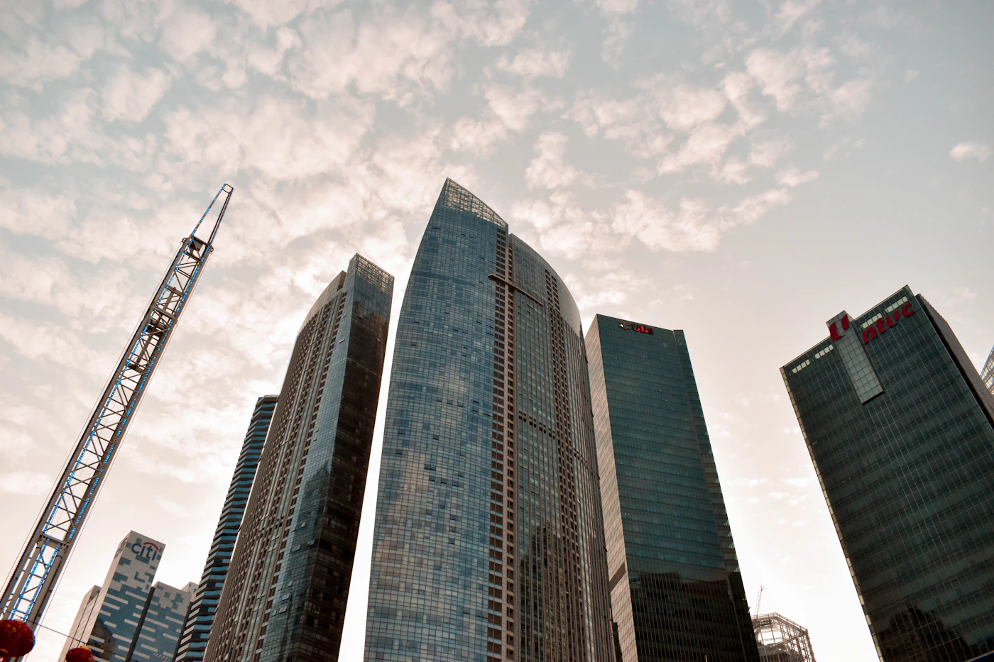Upward view of glass towers at Marina Bay Financial Centre beneath a clouded sky
