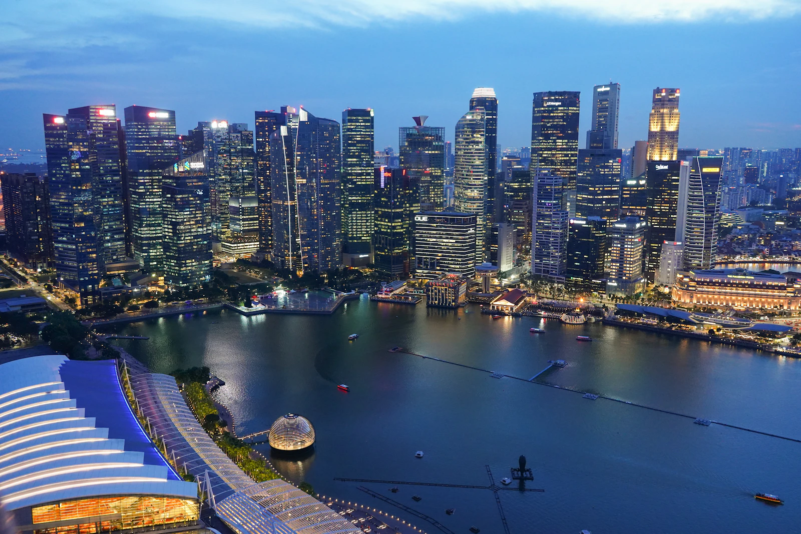 Aerial view across Marina Bay to Singapore's illuminated city skyline at blue hour